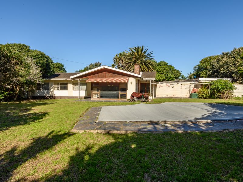 Rear view of the property featuring a swimming pool with a cover, a paved patio area, and a brick chimney.