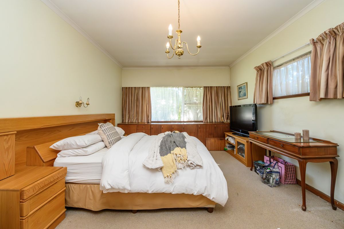 Spacious bedroom featuring extensive built-in timber cabinetry, integrated headboard, neutral carpeting, and classic coving detail.