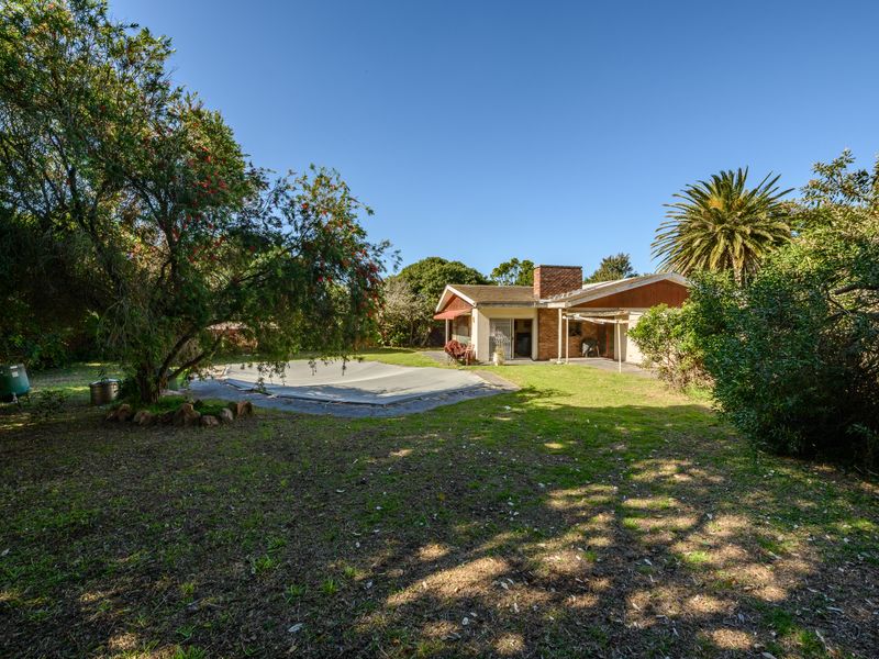 Rear view of the property featuring a swimming pool with cover, a covered patio area, and a spacious garden with mature trees.