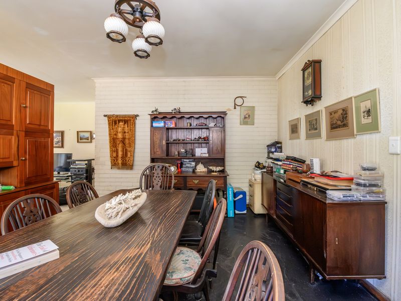 Dining room featuring a painted brick accent wall, traditional wallpaper, and dark flooring, offering a classic layout ready for modern updates.