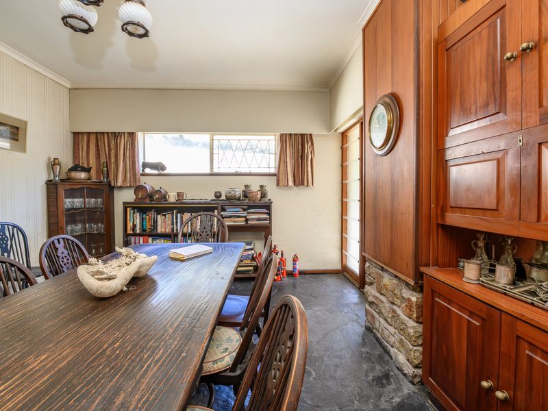 Dining room featuring slate flooring, a stone feature wall, and extensive built-in timber cabinetry, offering a classic, character-filled space for family meals.