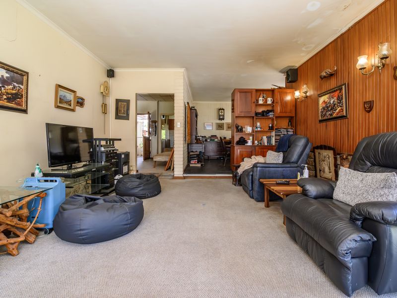 Spacious living room featuring wood paneling, built-in shelving, and a stone fireplace surround, requiring cosmetic updates to the ceiling and flooring.