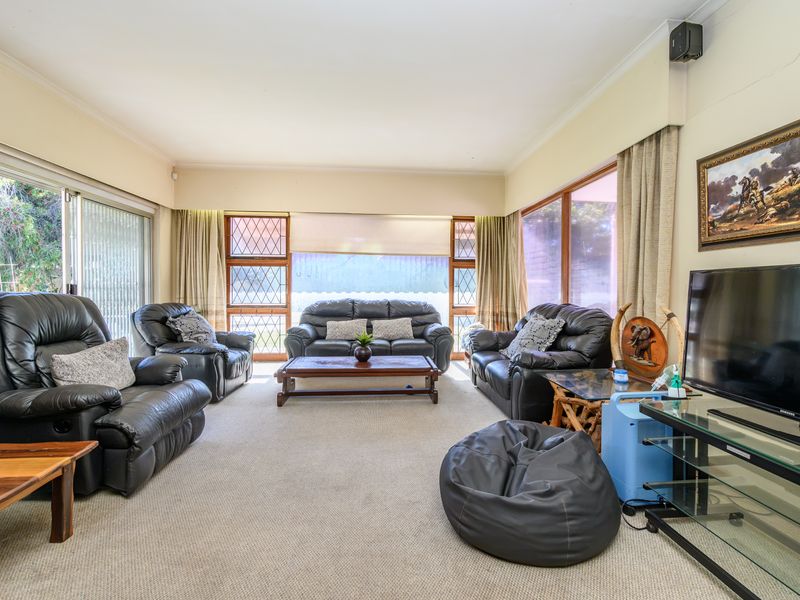 Spacious living room featuring large sliding glass doors, leaded glass windows, and neutral carpeting, offering a bright and comfortable area for relaxation.