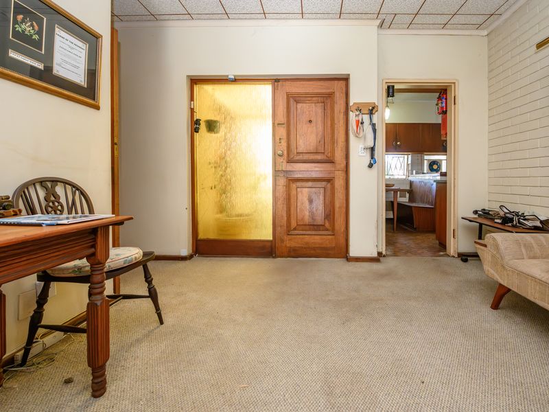 Entrance foyer featuring a solid timber front door with textured glass sidelight, exposed brick wall detail, and acoustic tile ceiling.