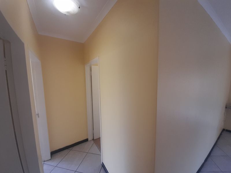 A clean, empty hallway featuring tiled flooring and neutral wall finishes, providing access to multiple rooms within the flat.