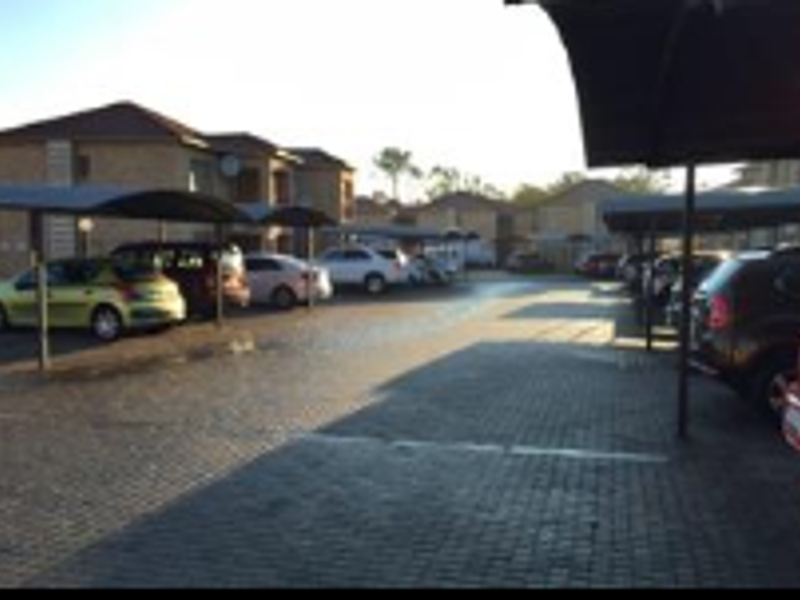 Outdoor parking area featuring paved ground and multiple covered parking bays within the residential complex.