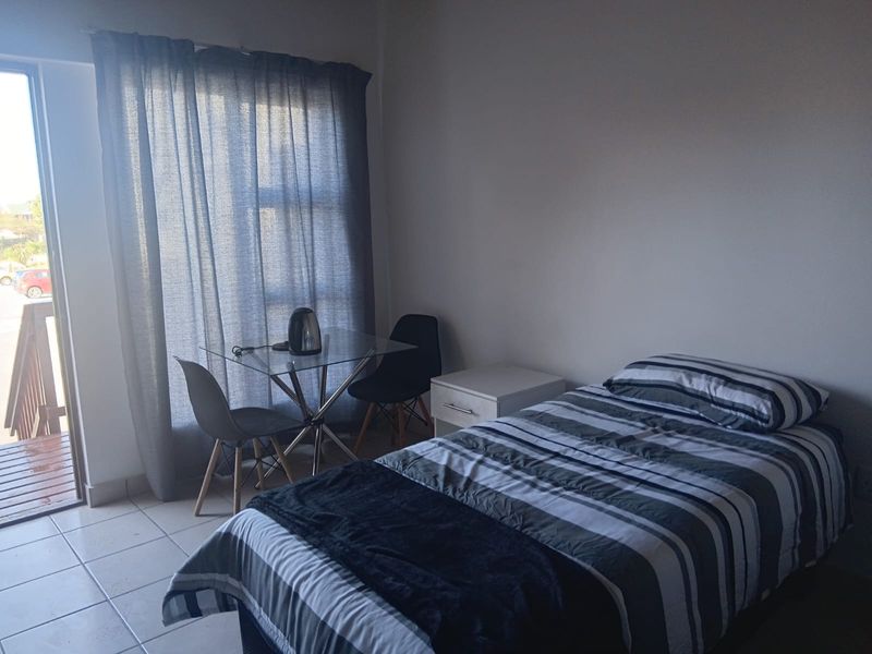 A functional bedroom featuring tiled flooring and a sliding glass door providing access to an outdoor area.