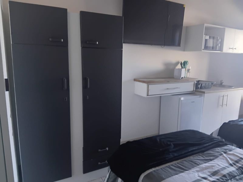 Compact open-plan living area featuring a kitchenette with built-in cabinetry, sink, and countertop space.