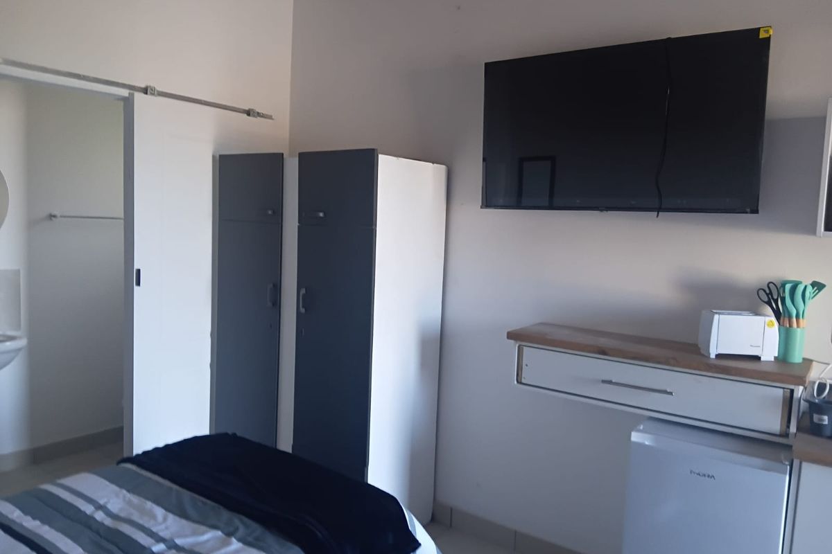 A bedroom featuring a sliding door, built-in storage cabinetry, and a wall-mounted shelf unit.