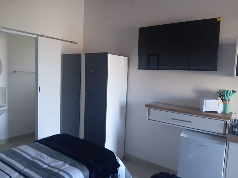 A bedroom featuring a sliding door, built-in storage cabinetry, and a wall-mounted shelf unit.