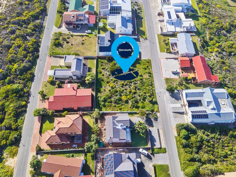 An aerial view of a vacant residential plot situated within an established neighborhood, offering a clear perspective of the surrounding properties and street access.
