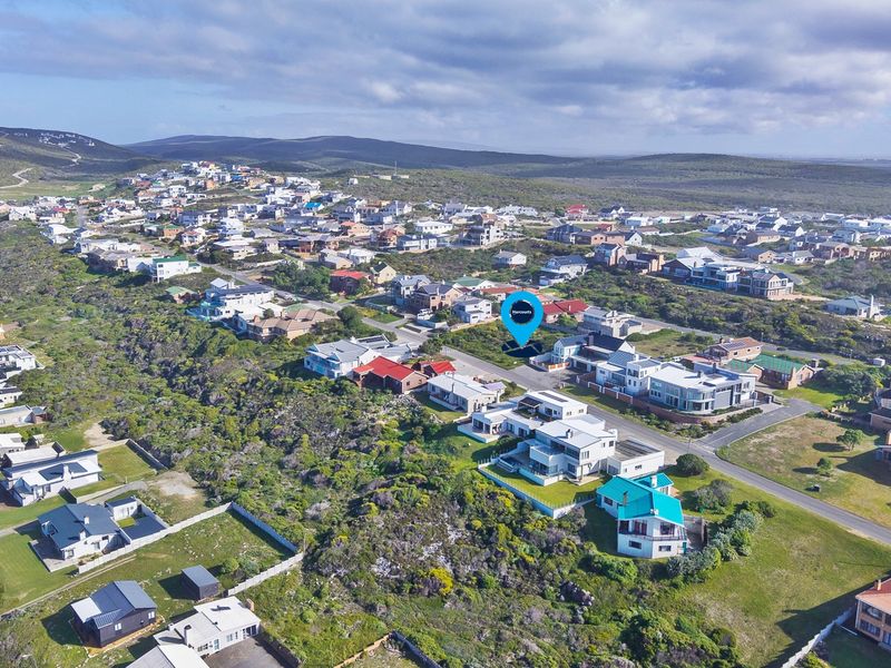 An aerial view of a residential coastal neighborhood, highlighting the location of the vacant land plot within the established community.