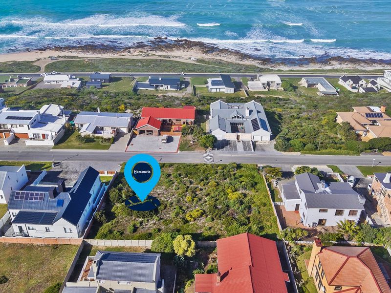 An aerial view of a vacant residential plot situated in a coastal neighborhood, offering proximity to the ocean and established surrounding properties.