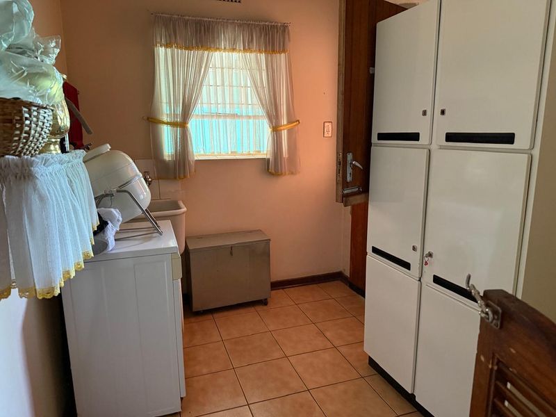 A functional laundry room featuring tiled flooring, a utility sink, and built-in storage lockers, providing practical space for household tasks.