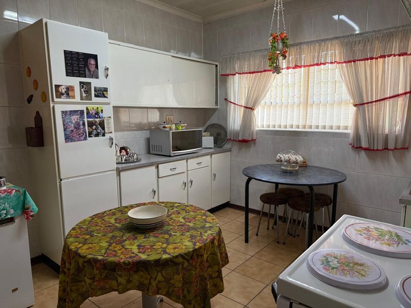 A functional kitchen featuring white built-in cabinetry, tiled splashbacks, and tiled flooring, offering a practical layout for daily meal preparation.