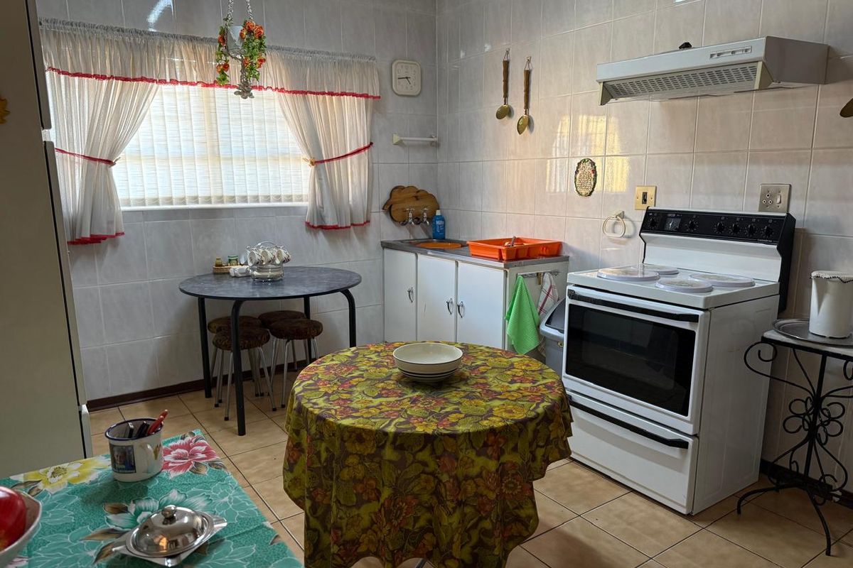 A functional kitchen featuring tiled walls and flooring, equipped with a freestanding stove, extractor fan, and built-in cabinetry.