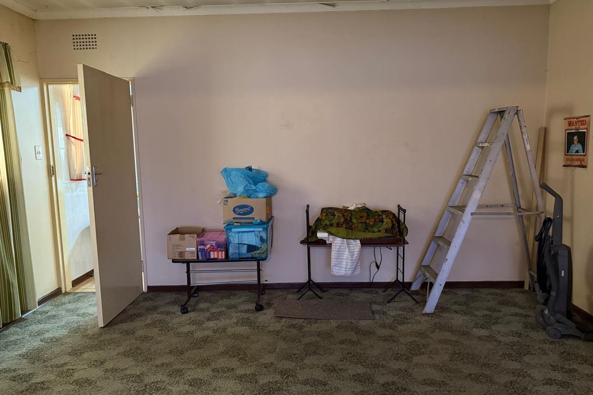 A vacant living room featuring dated carpet flooring and visible signs of wear on the ceiling and walls, offering potential for renovation.