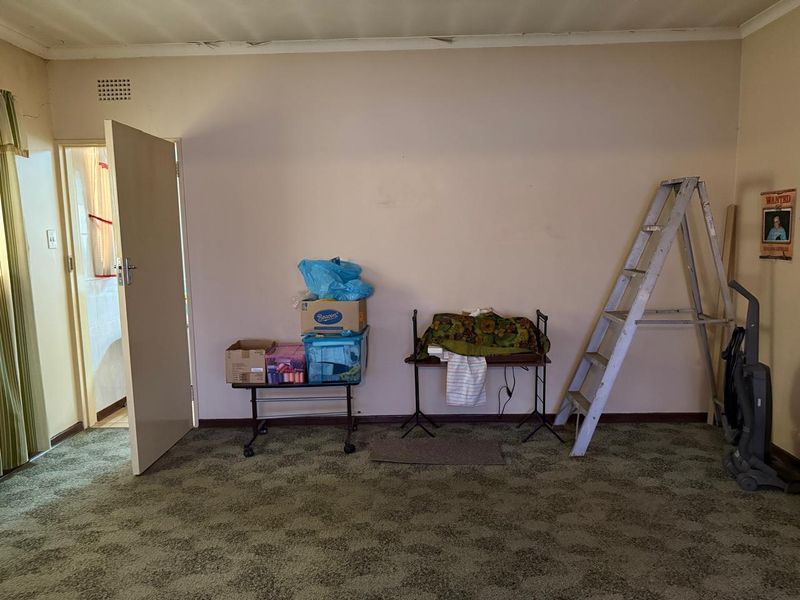 A vacant living room featuring dated carpet flooring and visible signs of wear on the ceiling and walls, offering potential for renovation.