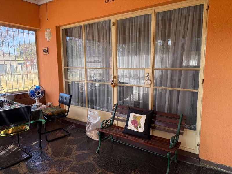 A covered patio area featuring stone flooring and large metal-framed glass doors, providing a functional outdoor space for relaxation.