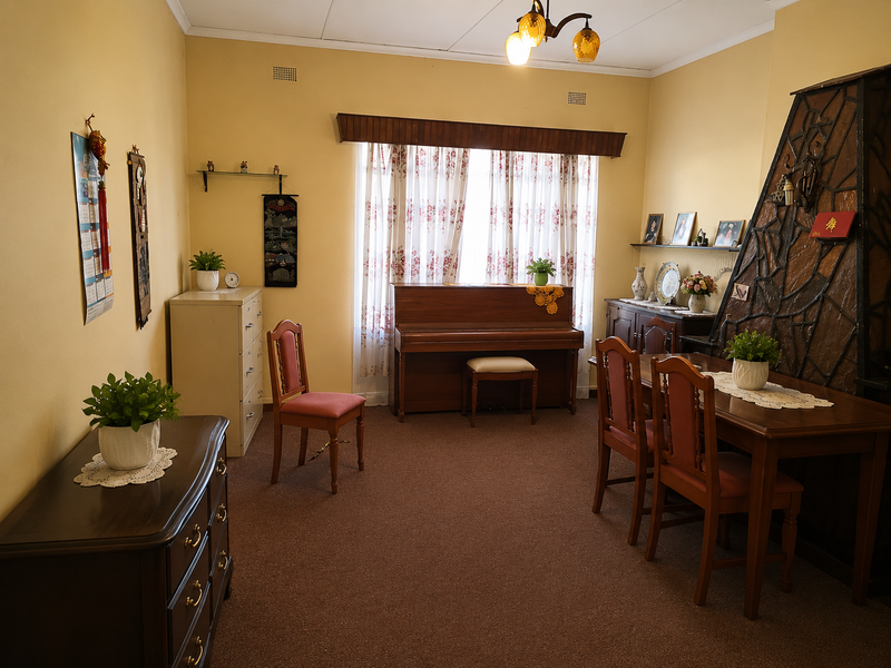 A traditional living room featuring a decorative fireplace, carpeted flooring, and a large window with a wooden valance.