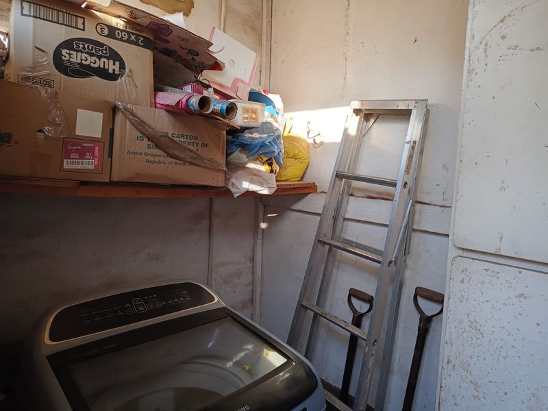 A small utility or laundry area featuring built-in shelving and wall-mounted storage space, currently used for general storage.