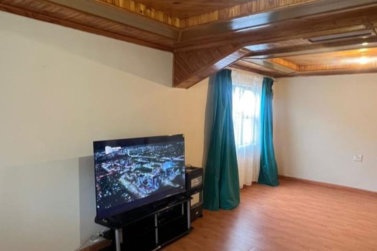 Living room featuring a distinctive timber-clad ceiling and laminate flooring, providing a warm and traditional aesthetic.