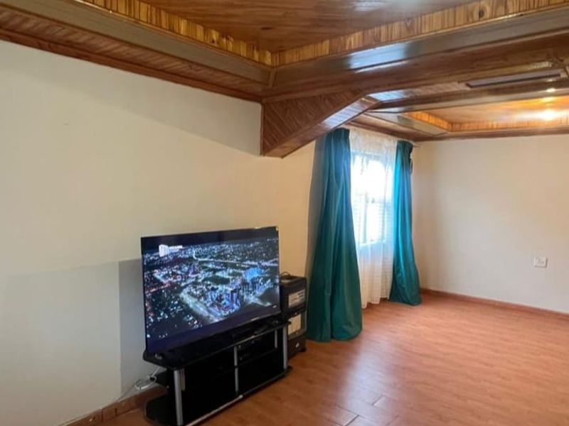 Living room featuring a distinctive timber-clad ceiling and laminate flooring, providing a warm and traditional aesthetic.
