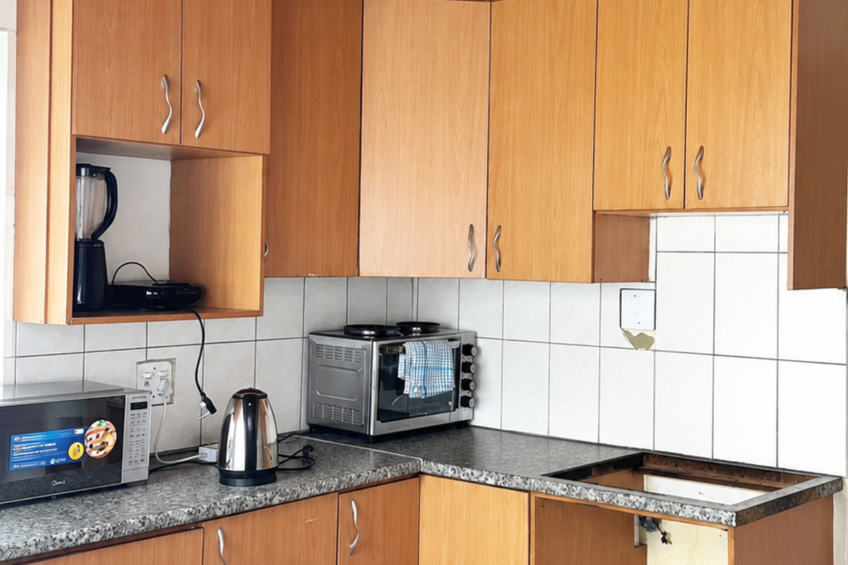 Kitchen featuring timber ceiling, laminate cabinetry, and granite-look countertops. The space requires repair to the missing appliance housing and electrical fixtures.