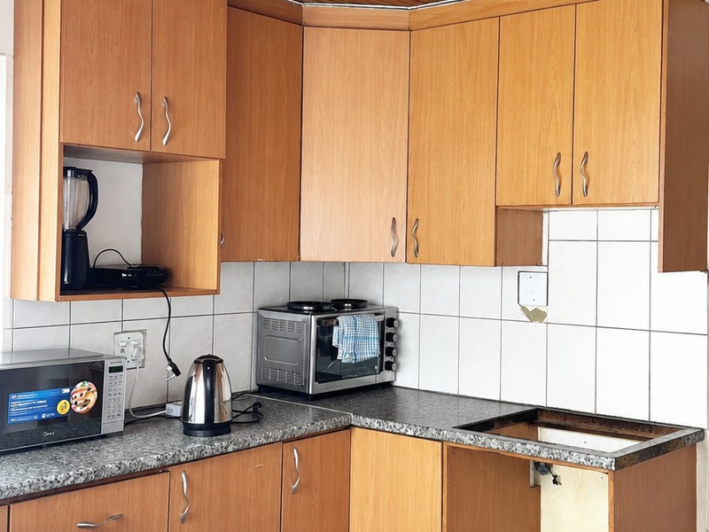 Kitchen featuring timber ceiling, laminate cabinetry, and granite-look countertops. The space requires repair to the missing appliance housing and electrical fixtures.