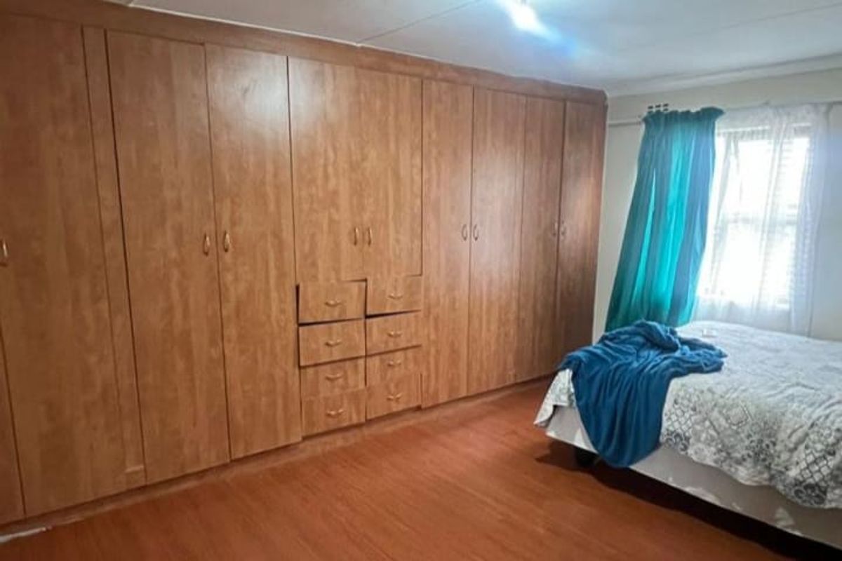 A bedroom featuring extensive built-in wooden cabinetry and laminate flooring, offering ample storage space.