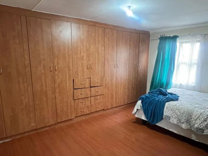 A bedroom featuring extensive built-in wooden cabinetry and laminate flooring, offering ample storage space.
