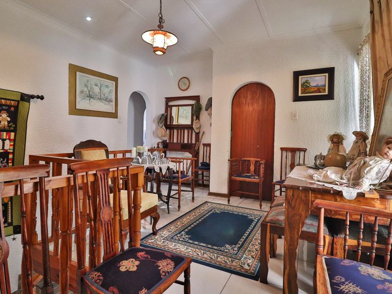 A living area featuring tiled flooring, an arched doorway, and a timber balustrade, providing a traditional layout with character architectural details.