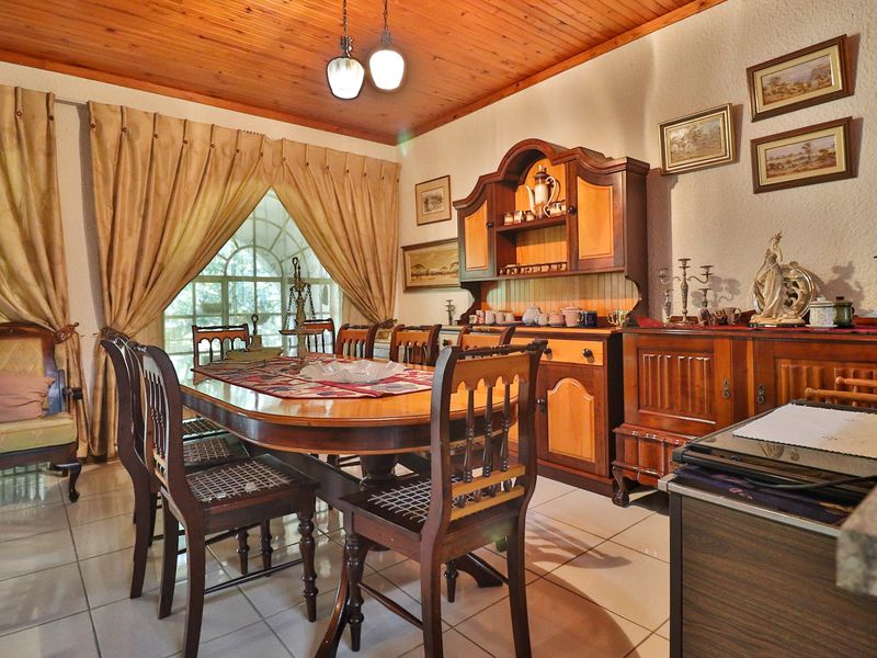 A traditional dining room featuring a timber-clad ceiling, tiled flooring, and an arched window, offering a classic and warm atmosphere.