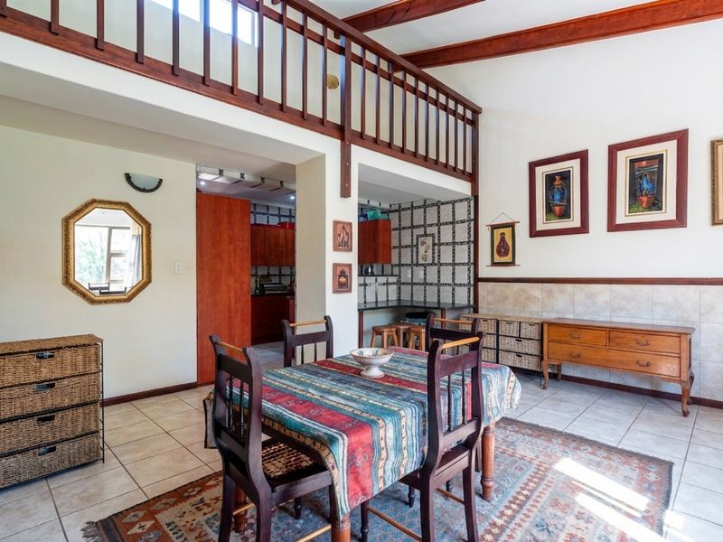 Open plan dining area featuring exposed timber ceiling beams, a mezzanine level with timber railing, and tiled flooring throughout.