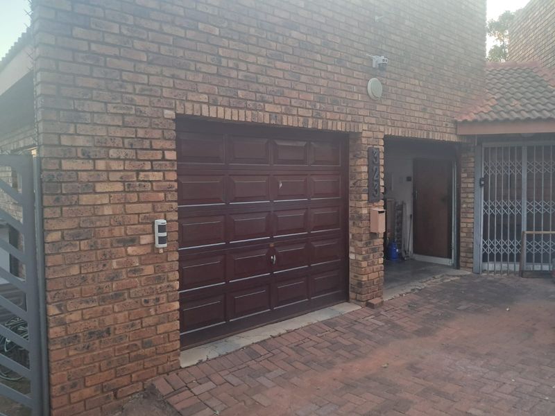 Front exterior view of the property featuring a brick facade, a dark-toned sectional garage door, paved driveway, and secure gated entrance.