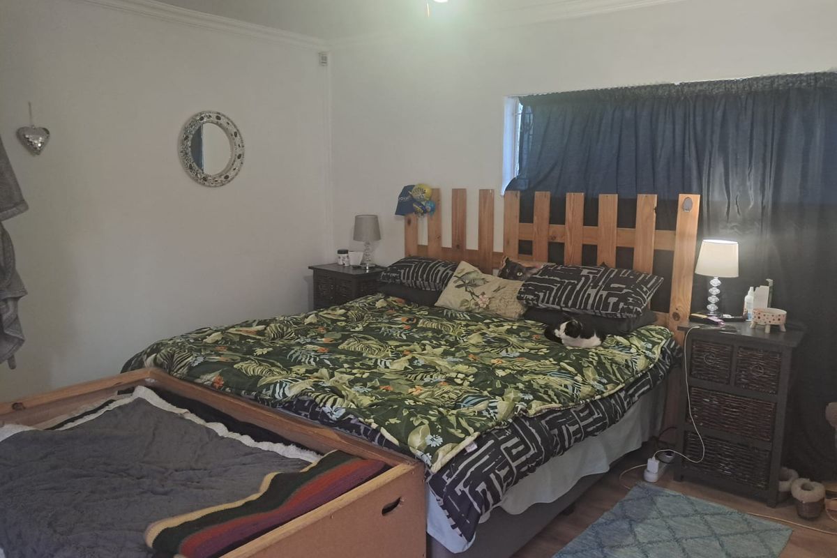 A standard bedroom featuring laminate flooring and ceiling cornicing, providing a functional space for rest.
