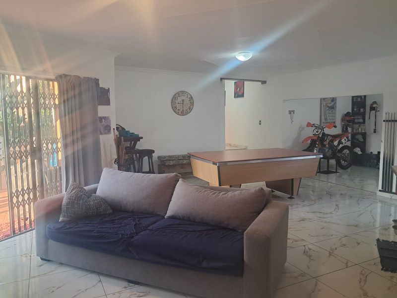 Spacious living area featuring polished marble-look floor tiles and a sliding security gate leading to the outdoor area.
