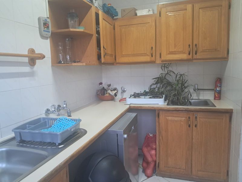 A functional scullery area featuring wooden cabinetry, a double stainless steel sink, and a gas cooktop, providing additional prep and wash-up space.