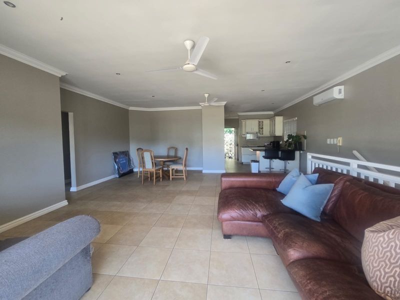 Spacious open-plan living and dining area featuring tiled floors, ceiling fans, and a functional kitchen with a breakfast bar.