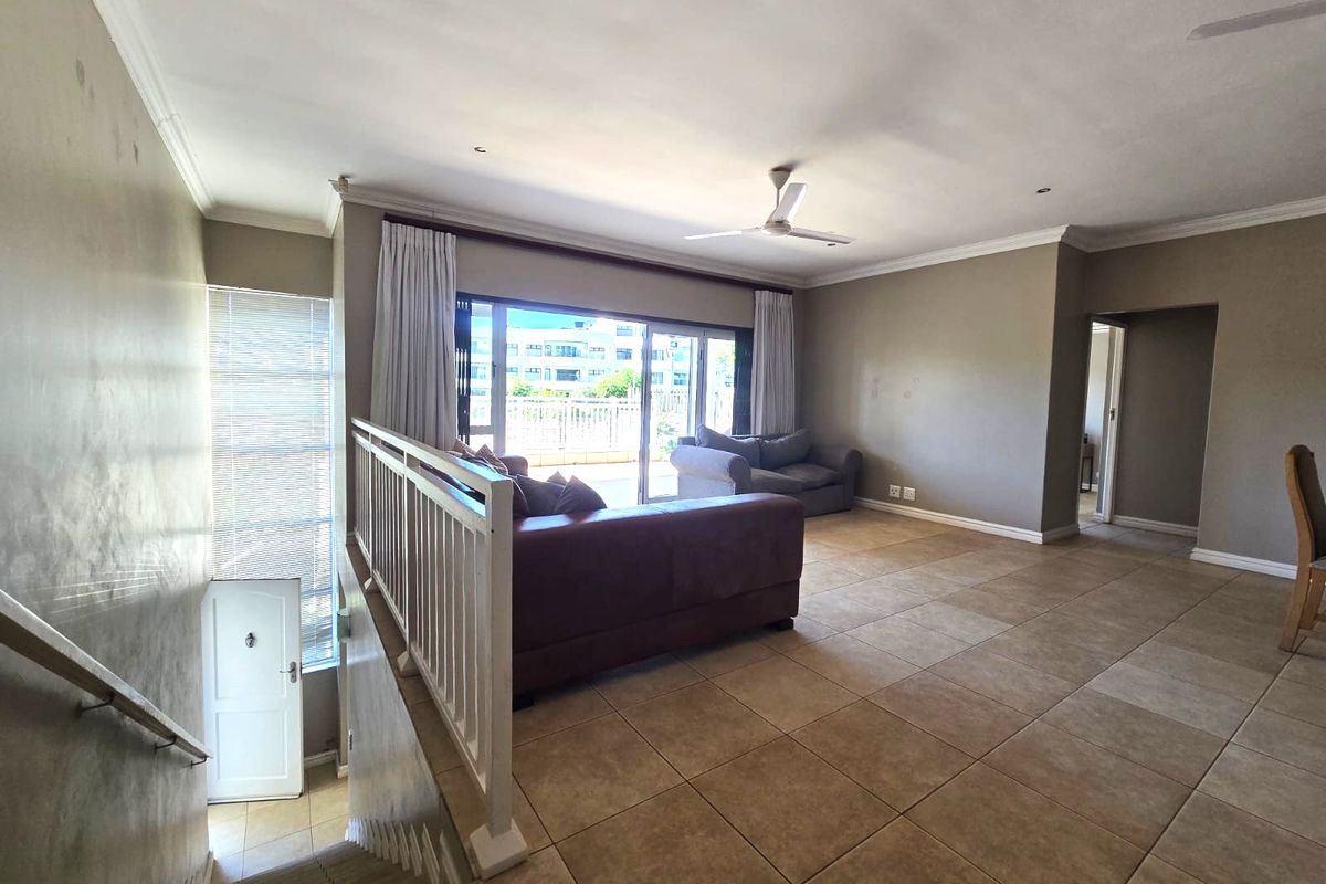Spacious living area featuring large format floor tiles, recessed lighting, a ceiling fan, and sliding glass doors leading to an outdoor balcony.