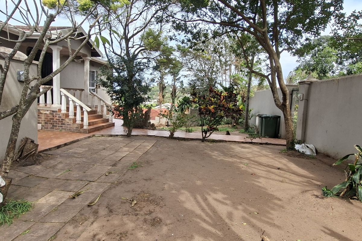 A rear garden area featuring a paved walkway, brick staircase leading to the house entrance, and perimeter boundary walls.