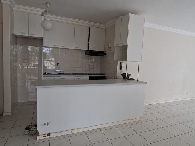 Open plan kitchen and living area featuring white cabinetry, a breakfast bar, and tiled flooring throughout.