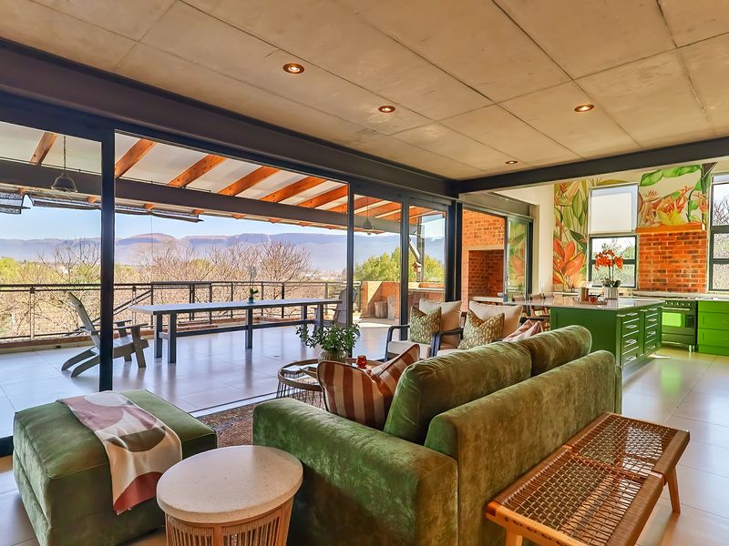 Spacious open-plan living and kitchen area featuring exposed concrete ceilings, large sliding doors opening to a covered patio, and modern kitchen cabinetry.