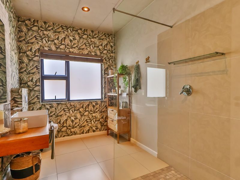 Modern bathroom featuring a spacious walk-in shower with glass screen, floating vanity with vessel sink, and decorative patterned wallpaper.