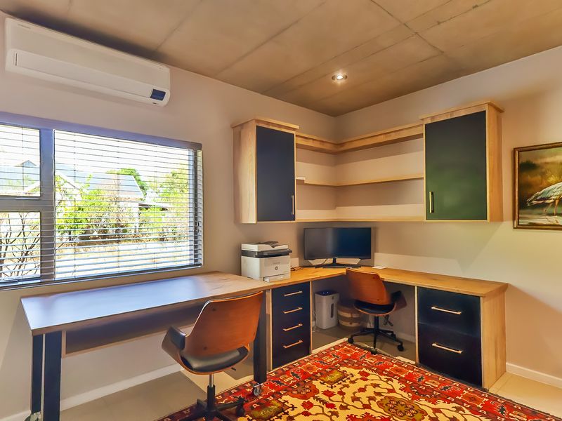 A functional home office featuring custom built-in desk space, integrated cabinetry, and a split-system air conditioning unit.