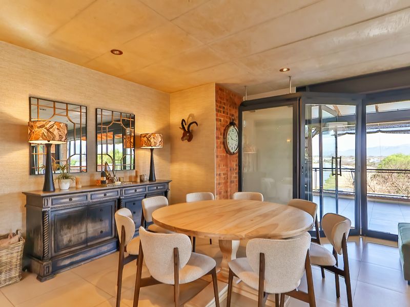 Elegant dining room featuring a textured feature wall, exposed brick accents, concrete ceiling, and large bi-fold glass doors leading to an outdoor balcony.