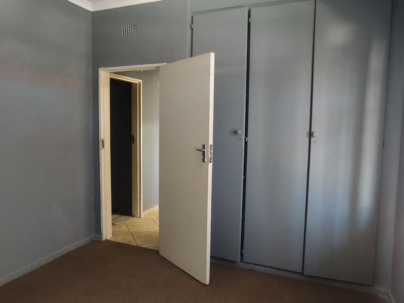 A vacant bedroom featuring built-in cupboards and neutral wall finishes, offering a blank canvas for potential interior updates.