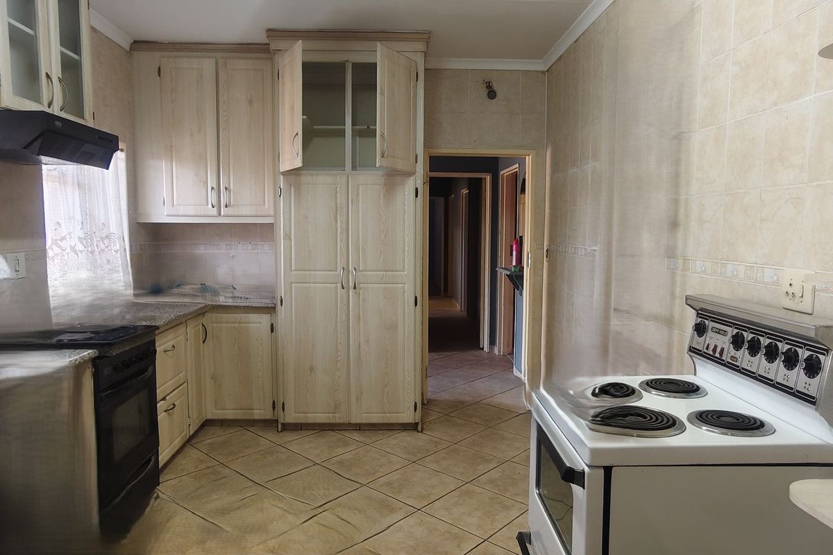 A functional kitchen featuring light-toned built-in cabinetry, tiled flooring, and wall tiling, offering a blank canvas for modern updates.