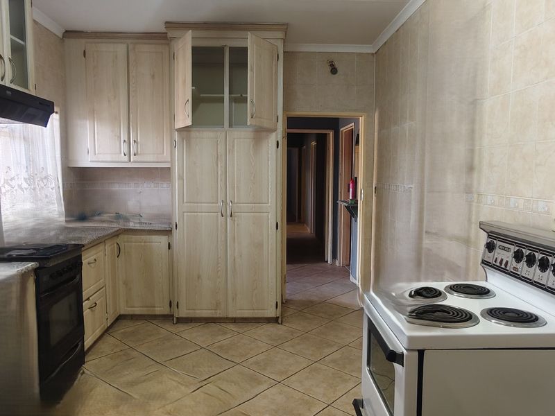 A functional kitchen featuring light-toned built-in cabinetry, tiled flooring, and wall tiling, offering a blank canvas for modern updates.