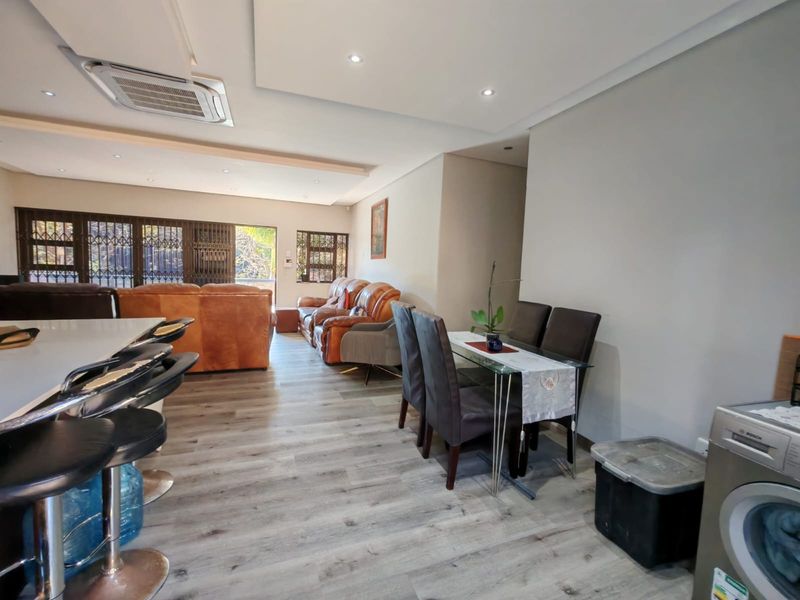 Spacious open-plan living and dining area featuring modern laminate flooring, recessed ceiling lighting, and integrated ducted air conditioning.